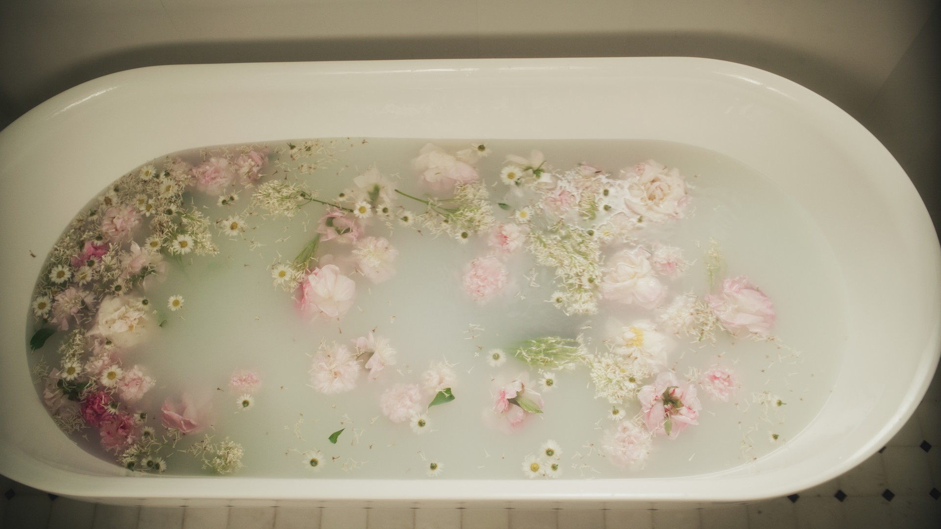 Spa day. Bath tub full of fragrant flowers for herbal therapy skin care