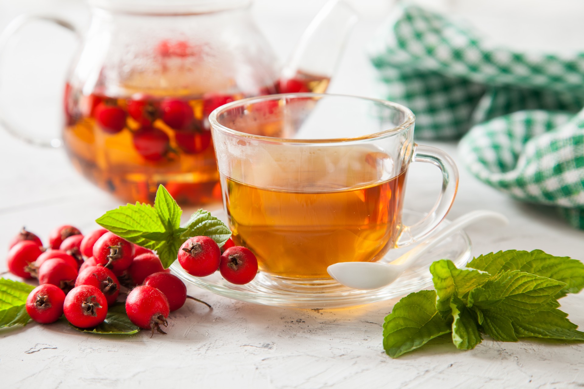 tea with a hawthorn and mint in a cup on a table, selective focus