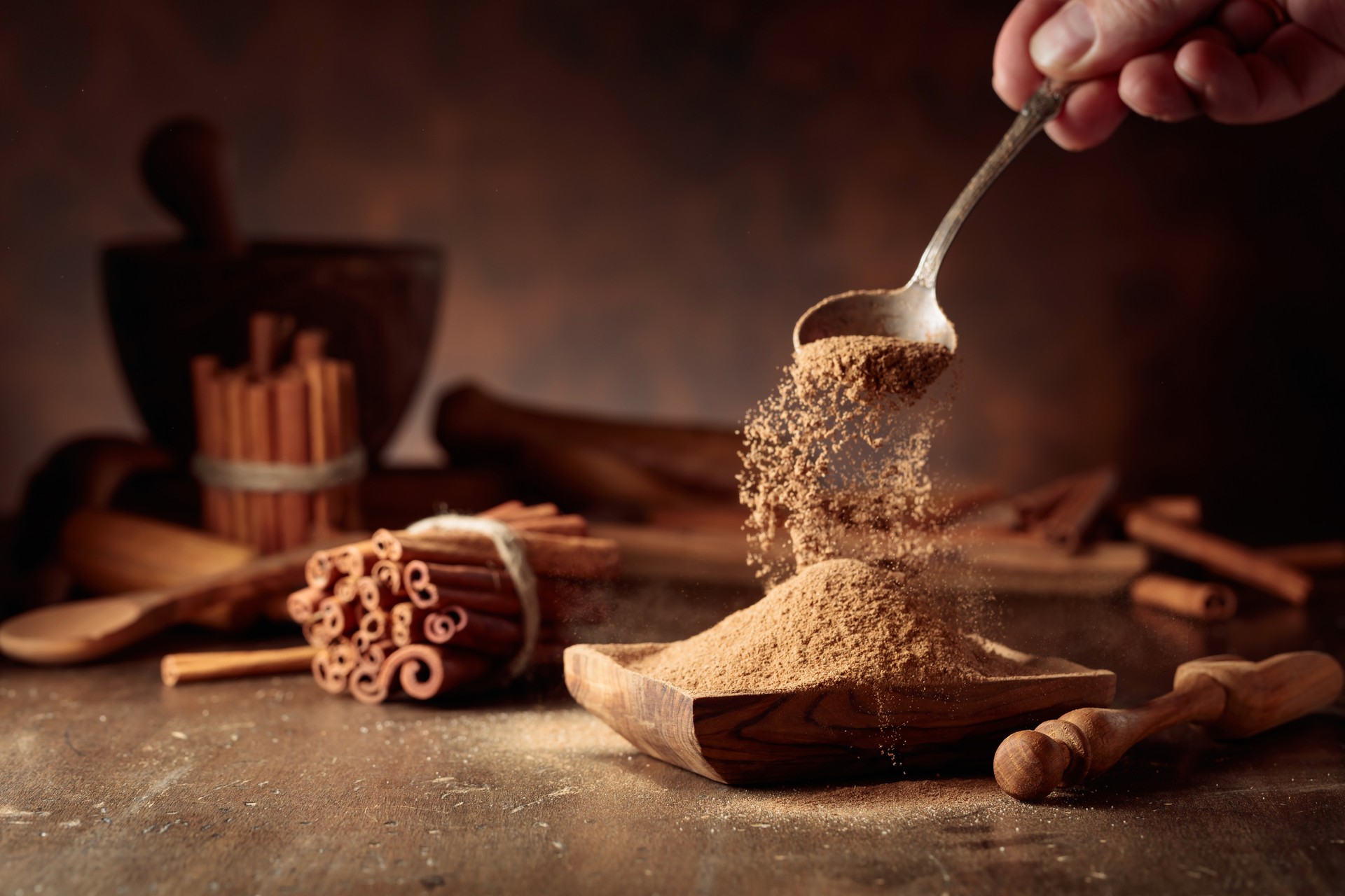 Cinnamon powder is poured into a wooden bowl.