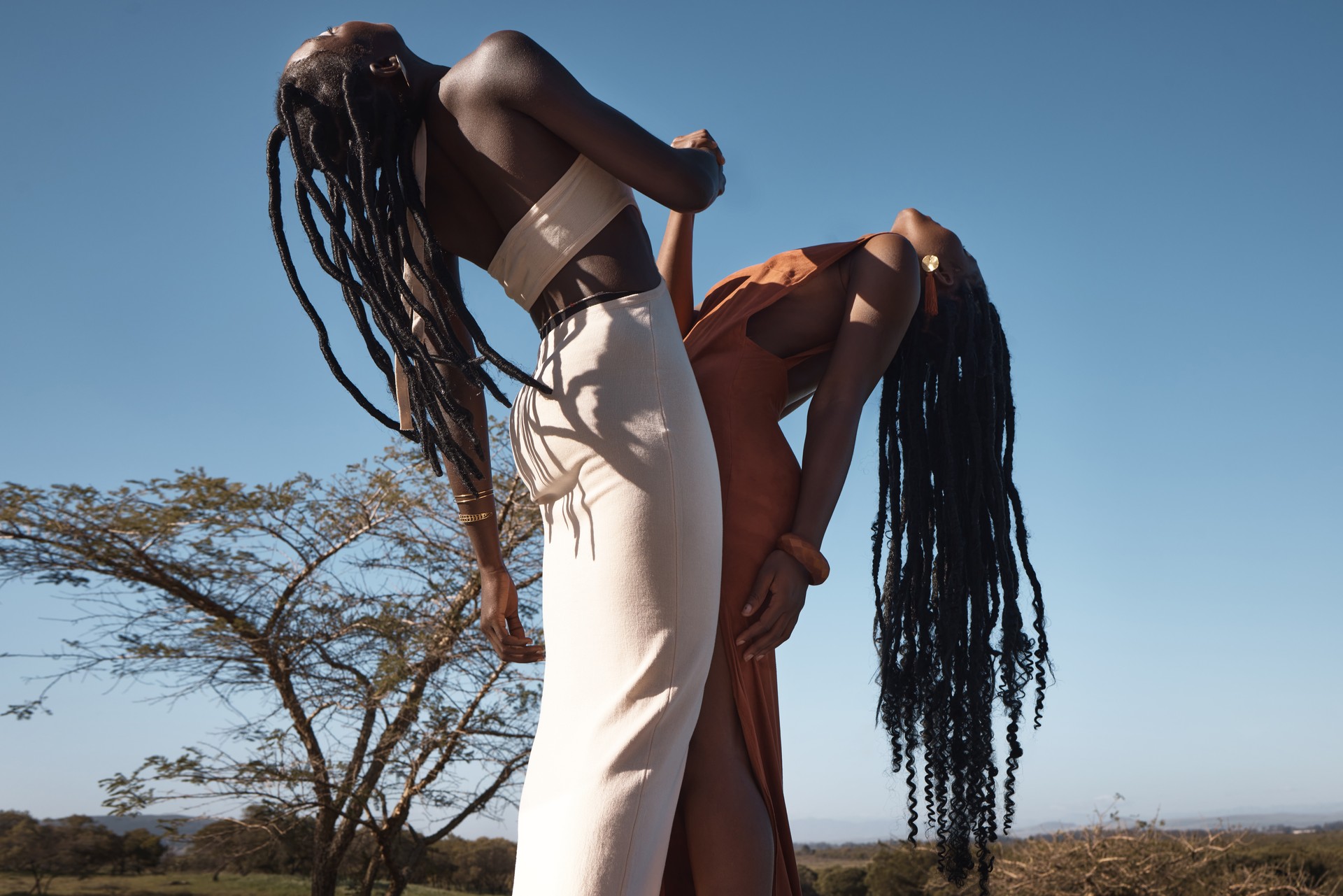 Shot of two attractive young women holding hands against an African nature background