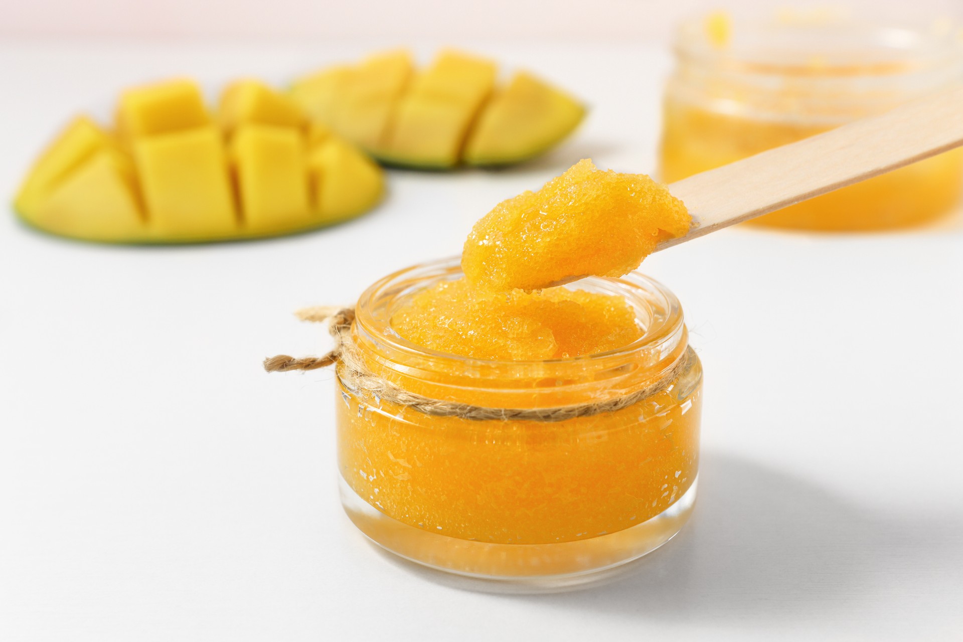 Tropical fruit sugar scrub for body care in a glass jar. Spa product from mango for skin cleansing.